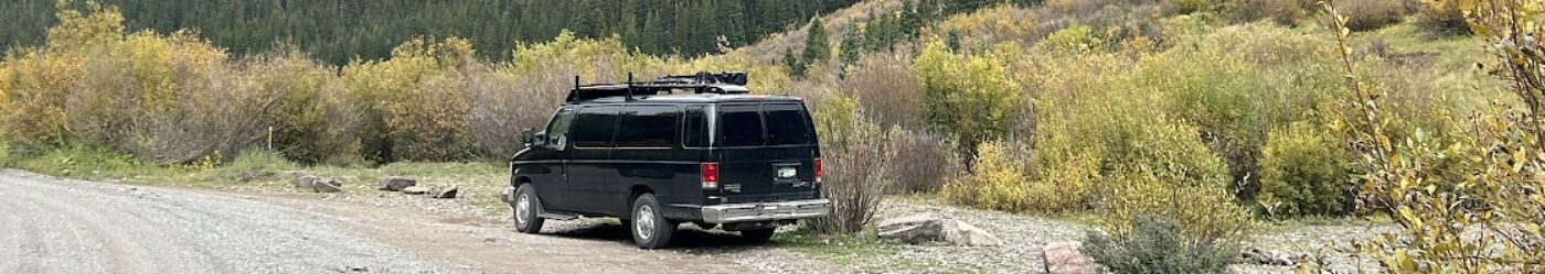 van parked on a dirt road with mountains in the background