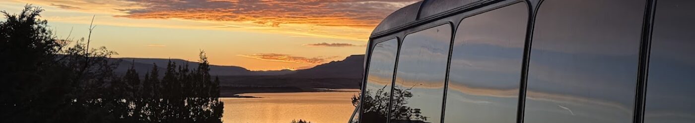 bus in front of a sunset with the sky reflected in its windows